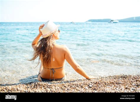 Vacances à la plage Jeune femme dans un chapeau et assis sur la plage de bikini vue de l