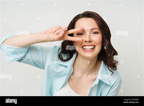 Portrait Of A Smiling Woman Showing A Victory Sign And Looking Into A