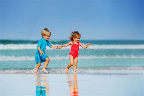 Bambino E Ragazza Corrono Sulla Spiaggia Di Sabbia A Mani Nude Fotografia Stock Immagine Di