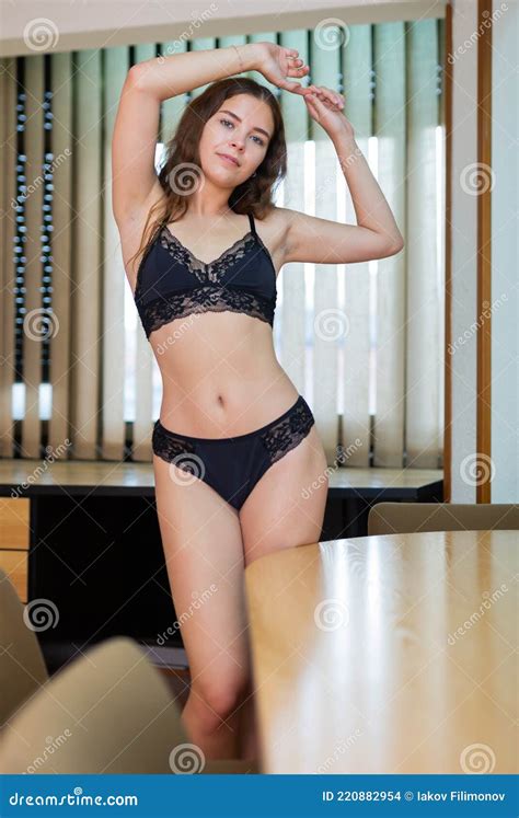 Woman In Black Lingerie Posing At Office With Hands Up Stock Photo