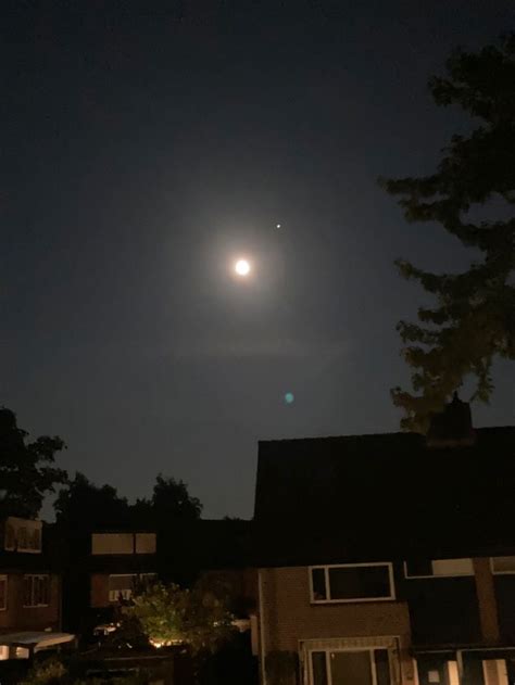 The Moon Shines Brightly In The Night Sky Over Some Houses And Lawn