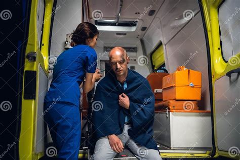 Nurse Puts Oxygen Mask On Man Sitting In Blanket In The Ambulance Car