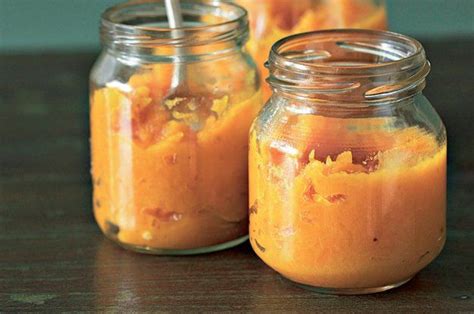 Two Mason Jars Filled With Orange Jello Sitting On Top Of A Wooden Table