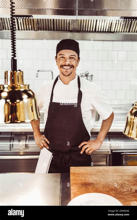 Portrait Of Happy Male Chef Standing With Hands On Hips In Commercial