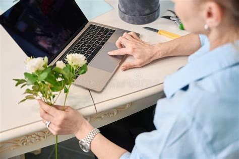 Cropped Photo Of Female Florist Sitting At Laptop With Flower Stock