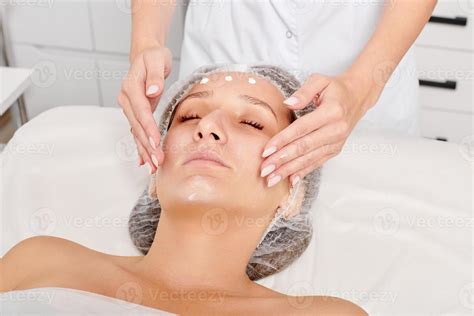 Beautician Rubbing Moisturizing Cream Mask Into Woman Face Skin For