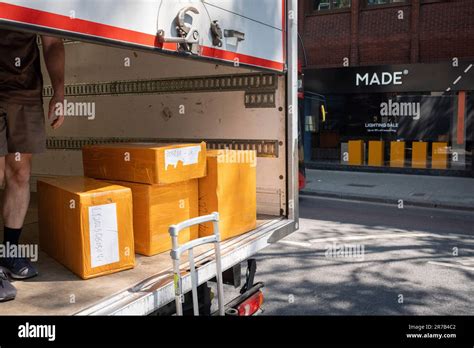 A UPS van driver unloads a stack of boxes from the rear of his vehicle for a nearby business on ...