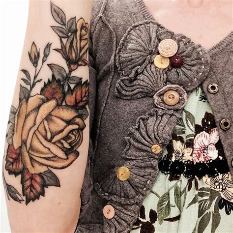 A Woman S Arm With Flowers On It And Buttons Attached To The Back Of