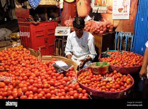 Un vendeur indien se trouve derrière une grande pile de tomates dans le