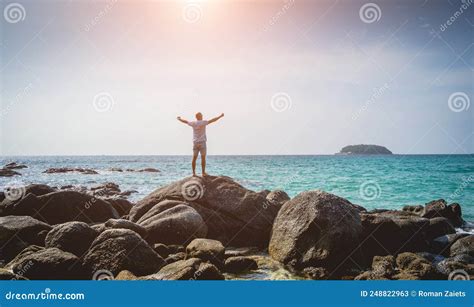 Young Man Relaxing On The Beach While Standing On An Stones Stock Image