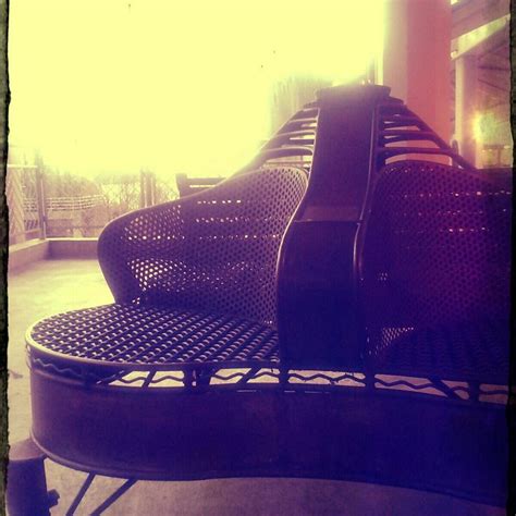 Two Empty Chairs Sitting Next To Each Other On A Metal Bench In Front