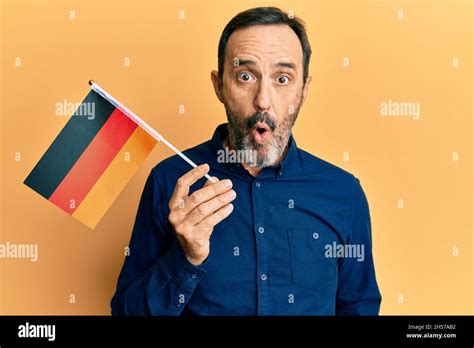 Middle Age Hispanic Man Holding Germany Flag Scared And Amazed With