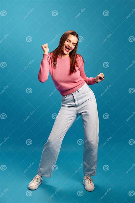 Happy And Positive Young Woman In Pink Sweater And Blue Jeans