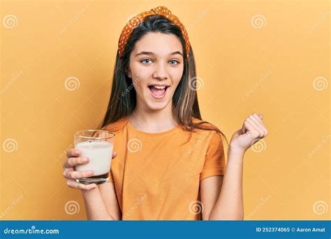 Young Brunette Girl Drinking A Glass Of Milk Screaming Proud