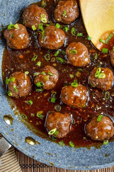 Meatballs And Gravy Are Being Cooked In A Skillet With A Wooden Spoon