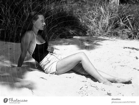 seitliches Ganzkörper Portrait einer jungen schönen Frau am Strand im