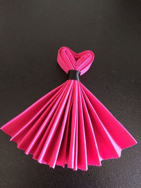 pink napkin, folded in the shape of a dress, tied with a black ribbon ...