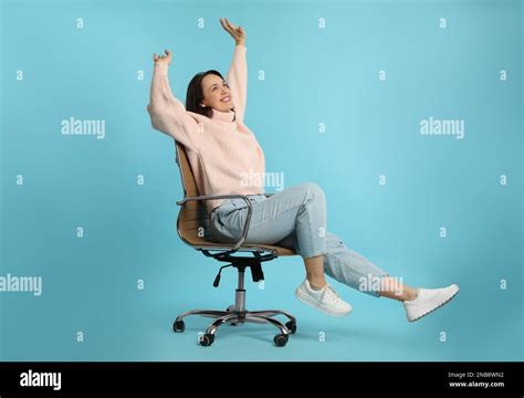 Mature Woman Riding In Comfortable Office Chair On Turquoise Background Stock Photo Alamy