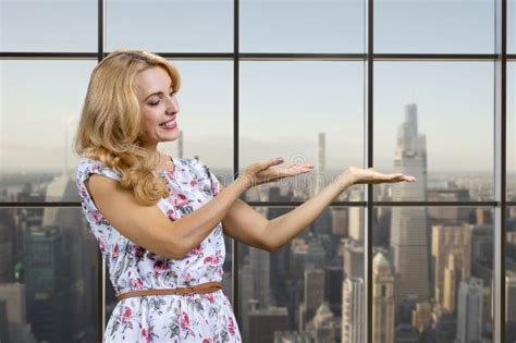 Caucasian Blonde Woman Shows Copy Place On Her Palm Standing Indoors Stock Photo Image Of