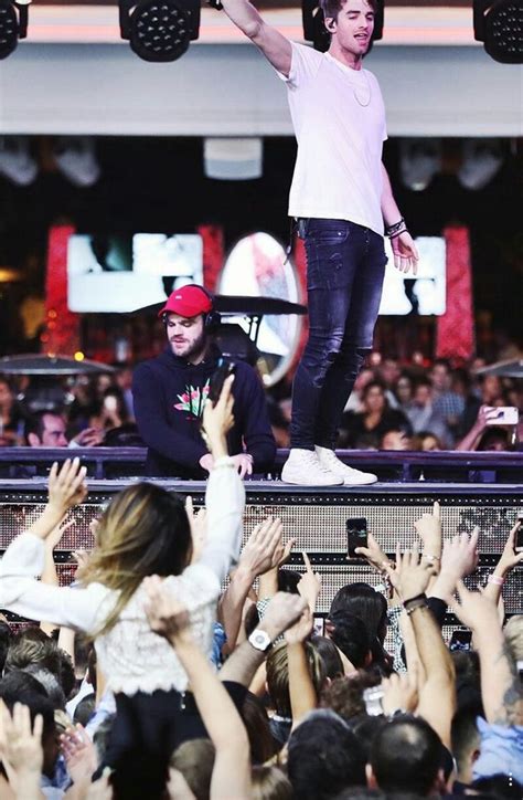 A Man Standing On Top Of A Stage Surrounded By People