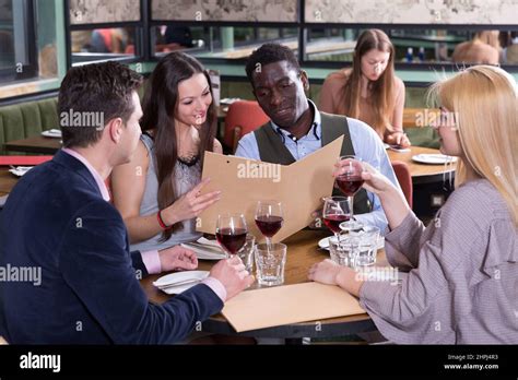 Happy people discussing restaurant menu Stock Photo - Alamy