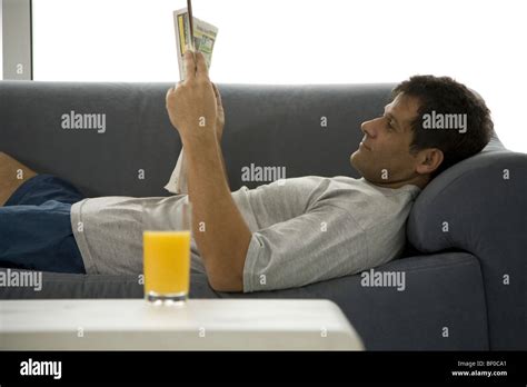 Side Profile Of A Mature Man Lying On A Couch And Reading A Newspaper Stock Photo Alamy