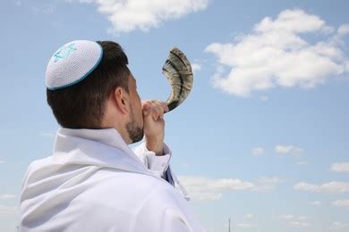 Jewish Man In Kippah And Tallit Blowing Shofar Outdoors Rosh Hashanah