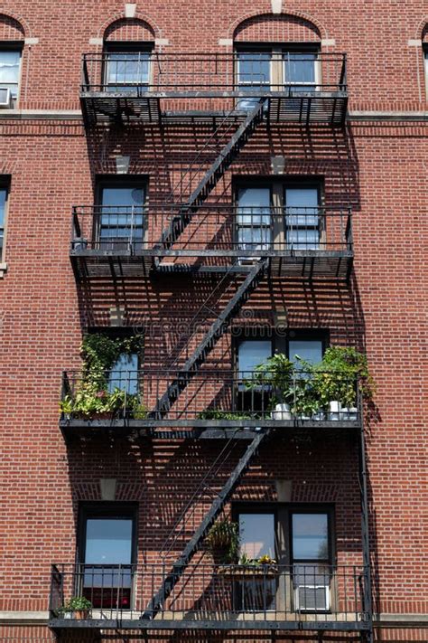 Fire Escapes With Potted Plants On An Old Brick Apartment Building In