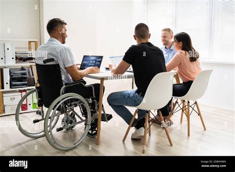 Disabled People In Wheelchair At Workplace Business Meeting Stock Photo