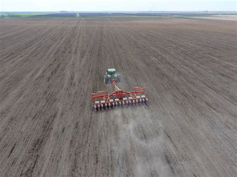 Premium Photo Sowing Of Corn Tractor With A Seeder On The Field Using