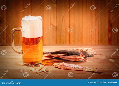 Taza Con La Cerveza Espumosa Y Los Pescados Secados En Fondo De Madera