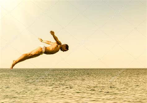 Cliff diver jumping in the sea against the sky at sunset - Concept of ...