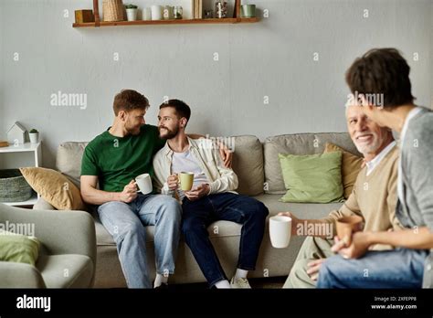 A Gay Couple Sits On A Couch With Parents Enjoying A Casual And Intimate Moment Together Stock