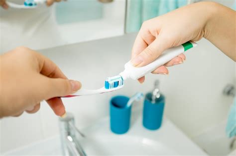 Closeup Mujer Poniendo Pasta De Dientes En El Cepillo De Dientes En El Baño Foto Premium