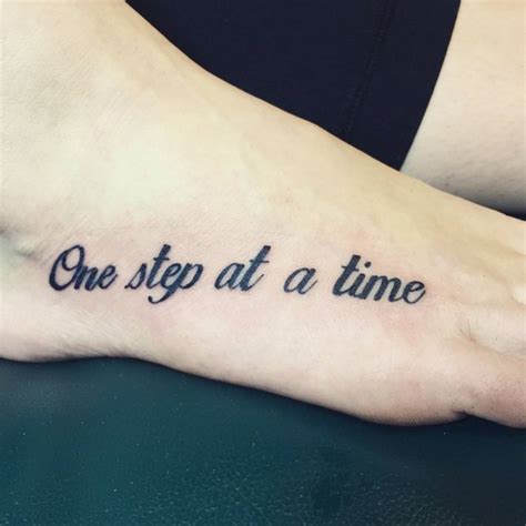 Foot tattoo saying "One step at a time" on Michela