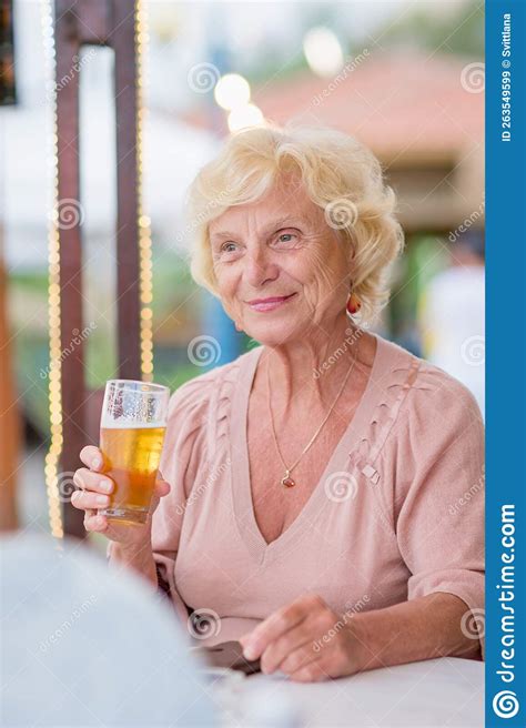 Mature Woman Sitting At A Table In A Summer Cafe And Drinking Beer Stock Image Image Of