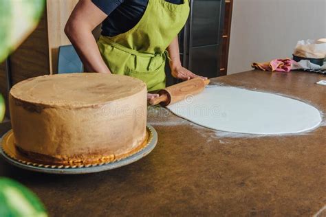 Woman Using Rolling Pin Preparing Pink Fondant For Cake Decorating