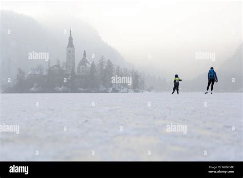 Mother and child ice skating on frozen lake Bled in winter. People walk ...