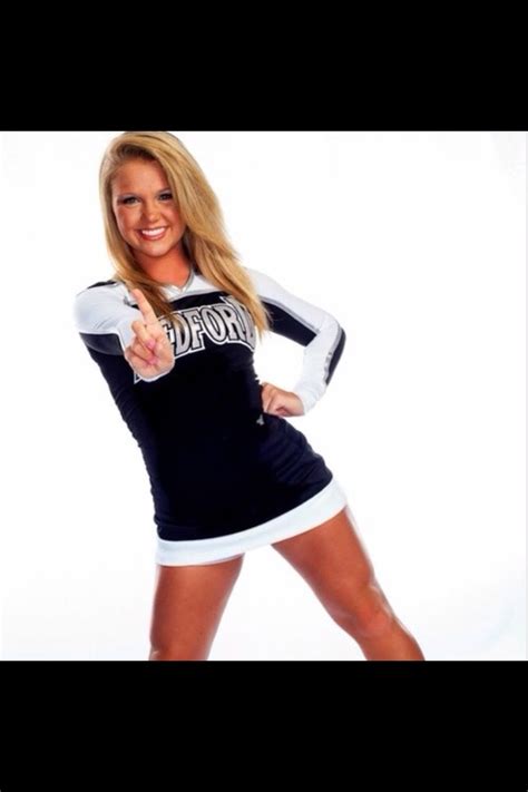 A Woman In A Cheerleader Uniform Pointing At The Camera