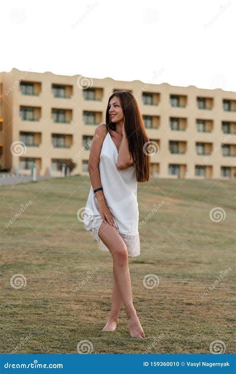 Une Jeune Fille Brunette Aux Cheveux Amples Debout Dans Le Mealow En Robe Blanche Touchant Le