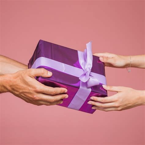 Free Photo Close Up Of Two Hands Holding Purple Gift Boxes Against