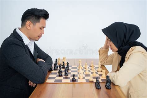 Homme En Costume Face Femme En Hijab En Jouant Aux échecs Photo stock