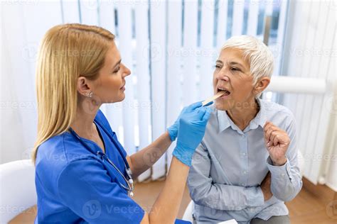 Senior Patient Opening Her Mouth For The Doctor To Look In Her Throat