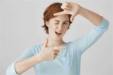 Insouciante Jolie Fille Rousse Posant Contre Le Mur Blanc Photo Gratuite