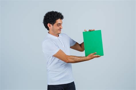 Jovem macho segurando a prancheta em camiseta branca calça e parecendo