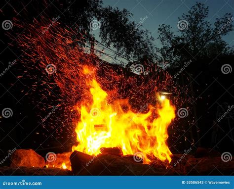 Sparks Bounce Off From A Bonfire At Night After A Log Thrown Into It