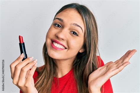 Young Brunette Woman Holding Red Lipstick Celebrating Achievement With