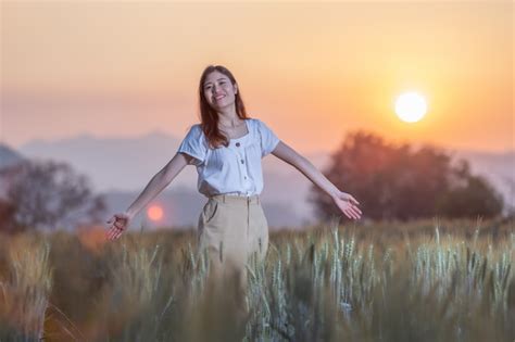 Mujer divirtiéndose en el campo de cebada al atardecer Foto Premium