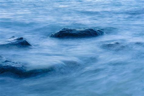 Long Exposure Smooth Ocean Wave Moving Into Rock Stock Photo