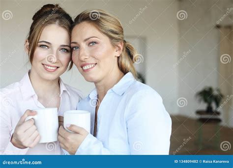 Beautiful Mature Mother And Her Adult Daughter Are Drinking Coffee